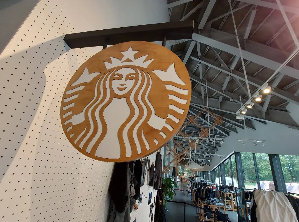店内に掲げられた木彫りのスターバックス・セイレーンロゴ看板と木組み天井